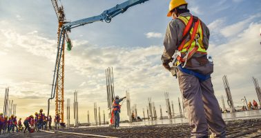 A construction worker control a pouring concrete pump on construction site and sunset background A construction worker control a pouring concrete pump on construction site and sunset background
