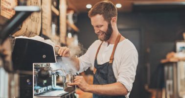 Smiling male barista preparing cappuccino in a coffee shop Smiling male barista preparing cappuccino in a coffee shop